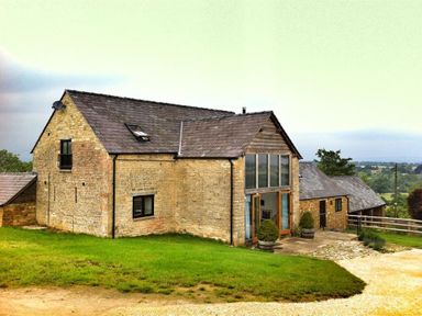 A stone house with large windows and a slate roof on a grassy plot at Stepwell in Moreton-In-Marsh