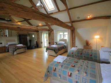 A bedroom with four single beds and wooden beams on the ceiling at Stepwell in Moreton-In-Marsh