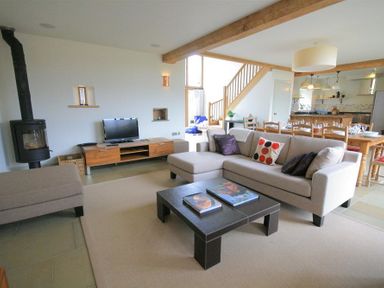 A living room with a sofa a coffee table a television and a wood stove next to a dining area at Stepwell in Moreton-In-Marsh