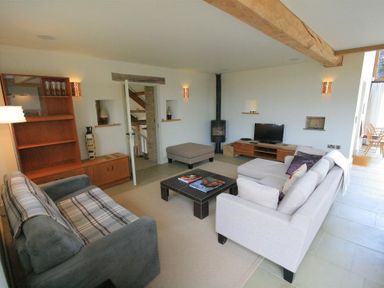 A living room with two sofas a coffee table a wooden cabinet a TV a small stove and an ottoman at Stepwell in Moreton-In-Marsh