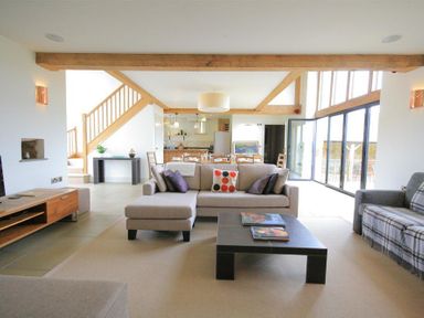 An open living room with a beige sofa, coffee table, staircase, and dining area at Stepwell in Moreton-In-Marsh