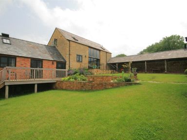 A large brick house with a wooden deck and stepped garden in a grassy yard at Stepwell in Moreton-In-Marsh