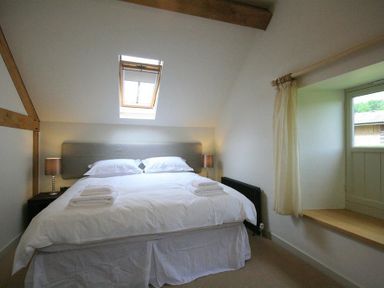 A bedroom with a double bed two bedside lamps a window with curtains and a skylight at Stepwell in Moreton-In-Marsh