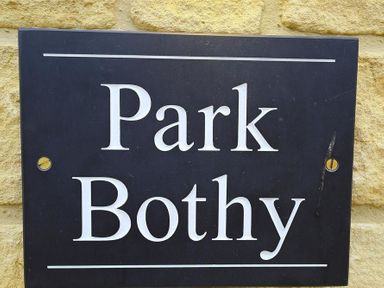 A black rectangular sign with white text reading Park Bothy mounted on a stone wall at Park Bothy in Wyck Rissington