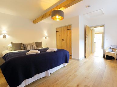 A bedroom with a double bed pillows and towels wooden floor and closet at Park Bothy in Wyck Rissington
