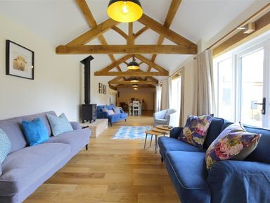 A living room with wooden beams on the ceiling and sofas along the walls at Park Stables in Wyck Beacon near Bourton-on-the-Water