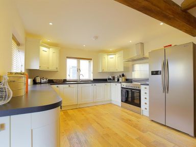 A kitchen with white cabinets stainless steel appliances and wooden floor at Park Stables Wyck Beacon near Bourton-on-the-Water