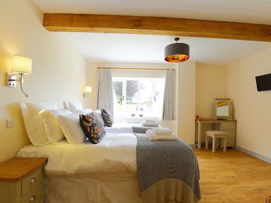 A bedroom with two beds a wooden beam on the ceiling and a desk at Park Stables Wyck Beacon near Bourton-on-the-Water