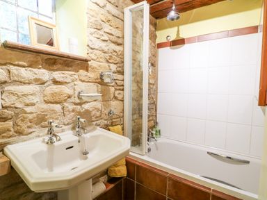 A bathroom with a pedestal sink and a bathtub with a shower at Hadcroft Cottage in Aston Magna