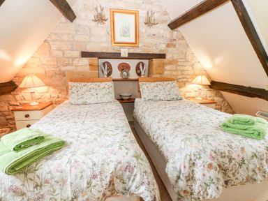 A bedroom with two single beds and floral bedding at Hadcroft Cottage in Aston Magna