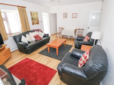 A living room with black leather sofas a wooden coffee table and a small dining table at Daffodil Cottage in Grange County Sligo