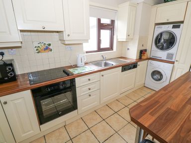 A kitchen with a stovetop oven dishwasher washing machine dryer and a countertop at Daffodil Cottage in Grange County Sligo