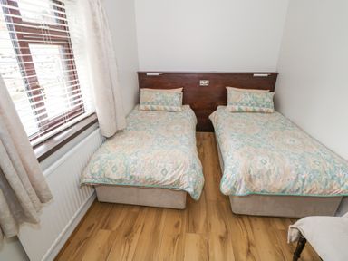 A bedroom with two single beds and a window with blinds and curtains at Daffodil Cottage in Grange County Sligo