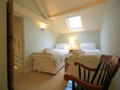 A bedroom with two single beds a wooden chair and a skylight window at Cider Press Cottage in Priston Village Bath