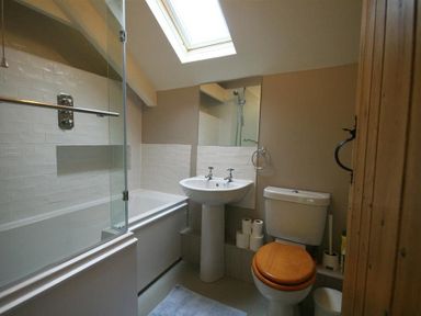 A bathroom with a bathtub shower combination sink toilet and skylight at Cider Press Cottage in Priston Village Bath