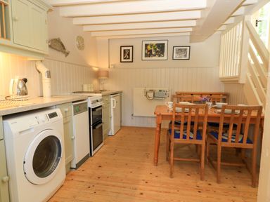 A kitchen with appliances and dining table at Cider Press Cottage in Priston Village, Bath