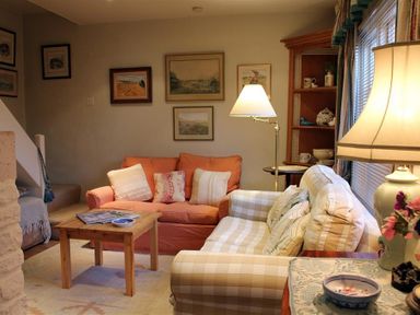 A living room with two sofas a wooden coffee table lamps and framed pictures on the wall at The Mews Cottage in Tisbury