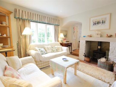 A living room with sofas a table a fireplace and lamps at The Mews Cottage in Tisbury