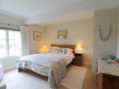 A bedroom with a bed and wooden furniture at The Mews Cottage in Tisbury