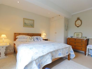A bedroom with a double bed bedside tables lamps a wooden dresser and a built in wardrobe at The Mews Cottage in Tisbury