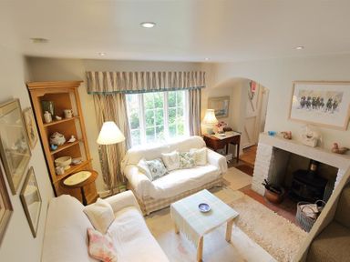 A living room with two sofas a coffee table a fireplace and a wooden cabinet at The Mews Cottage in Tisbury