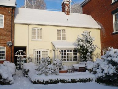A house with snow-covered roof bushes and garden furniture at The Mews Cottage in Tisbury