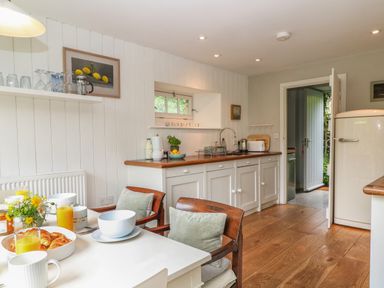 A kitchen with a dining table set for breakfast and wooden chairs at The Cart Barn in Ridge near Chilmark