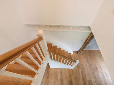 A wooden staircase with white railings in a hallway with wooden floors at The Cart Barn in Ridge near Chilmark