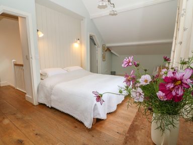 A bedroom with a double bed and a vase of flowers on a wooden table at The Cart Barn in Ridge near Chilmark