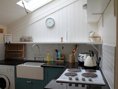 A kitchen with a sink, stove, kettle, toaster, and various utensils at Gun Hill Cottage in Heathfield