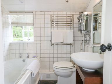A bathroom with a bathtub toilet sink and towel rack at Gun Hill Cottage in Heathfield