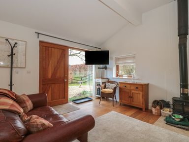 A living room with a leather sofa cushions a wood door and a mounted TV at Russet in Martin