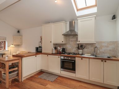 A kitchen with wooden countertops white cabinets a gas stove an oven and a skylight at Russet in Martin