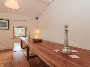 A wooden dining table with benches in a room with a framed picture window and a floor lamp at Russet in Martin