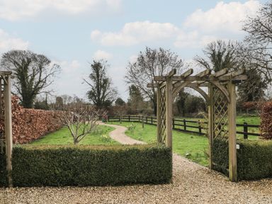 A garden pathway with a wooden arch and hedges along a gravel path at Russet in Martin