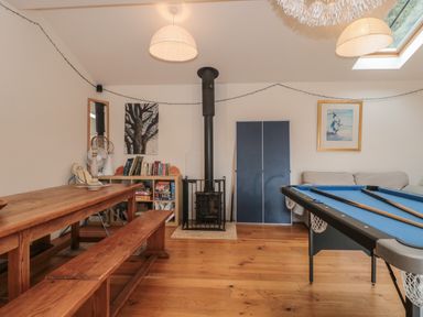 A room with a wooden bench and table a black stove a bookshelf a blue pool table and a sofa at Russet in Martin