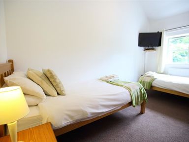 A bedroom with two single beds a lamp and a wall mounted tv at The Old Dairy in Flaxley