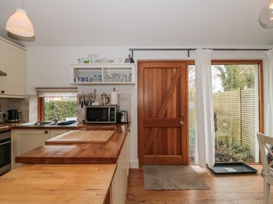 A kitchen with wooden countertops a wooden door and a window with white curtains at Pippin in Martin