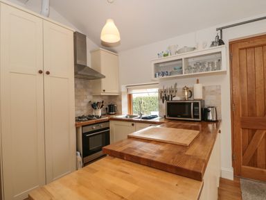 A kitchen with wooden countertops a gas stove an oven a microwave a toaster a kettle a knife rack and wooden cabinets at Pippin in Martin