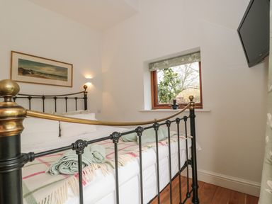 A bedroom with a metal bed frame with brass accents a window a wall-mounted TV and a framed painting at Pippin in Martin