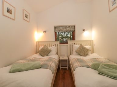 A bedroom with two single beds green towels and a wooden floor at Pippin in Martin