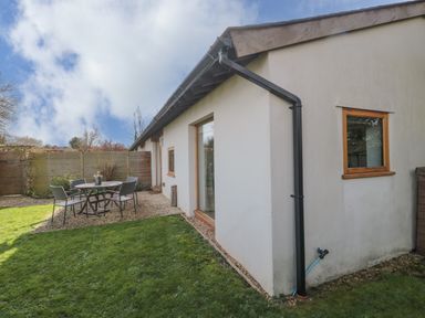 A backyard with a lawn dining table and chairs on a gravel area next to a white building at Pippin in Martin