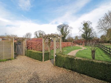A garden path with wooden pergolas and hedges at Pippin in Martin