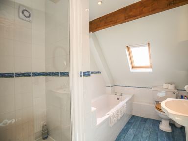 A bathroom with a bathtub a toilet sink a shower and a skylight window at The Coach House in Lympstone