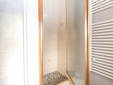 A tiled shower area with a glass door and a white radiator in a bathroom at Spring Cottage in Wroxton