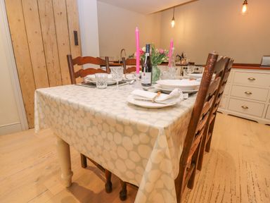 A dining table set with plates glasses and pink candles in a kitchen at Bridge Studio in Broad Chalke