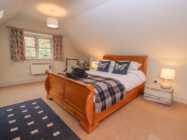 A bedroom with a wooden bed and blue butterfly cushions at Bridge Studio in Broad Chalke