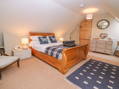 A bedroom with a wooden bed and bedside tables with lamps at Bridge Studio in Broad Chalke