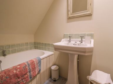 A bathroom with a bathtub a pedestal sink a mirror and towels at Bridge Studio in Broad Chalke