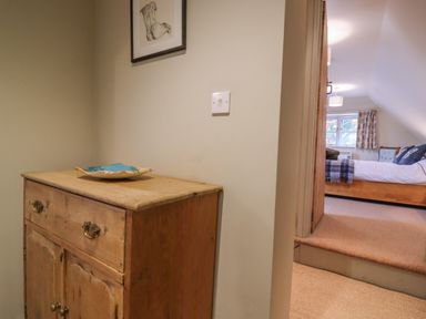 A wooden cabinet with a decorative plate and a framed drawing above at Bridge Studio in Broad Chalke